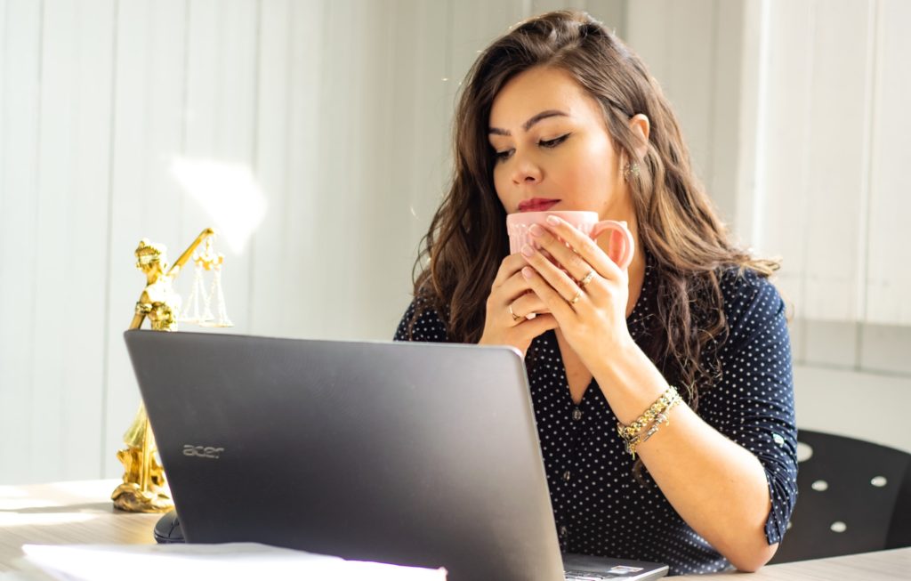 Woman sitting at computer holding cup of coffee